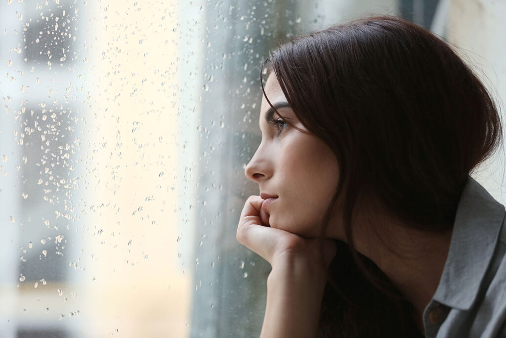 woman looking out of the window considers what is seasonal depression